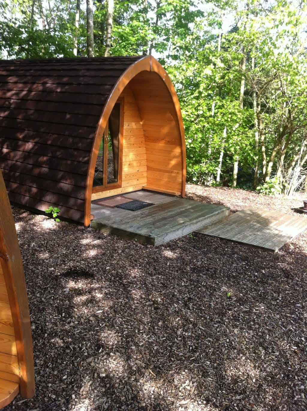 A glamping hut in the lake district. It is a curved wooden building that looks like a curved shed.