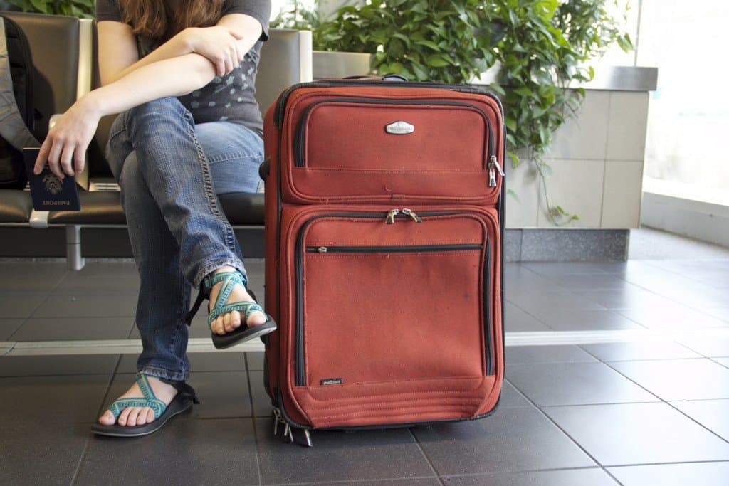 girl sitting next to suitcase