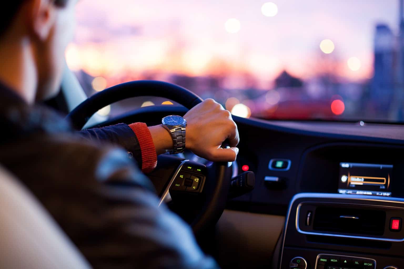 A man seen from behind driving a car at night