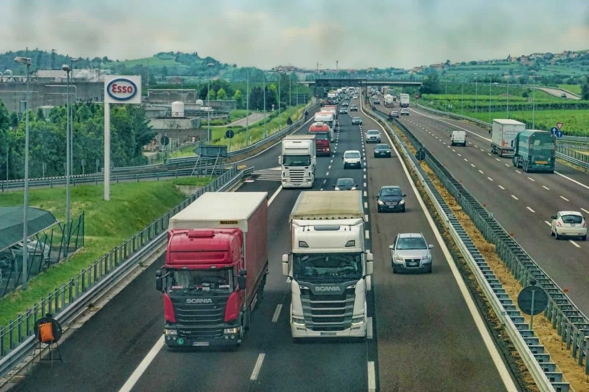 Two trucks on a motorway with cars and other trucks behind