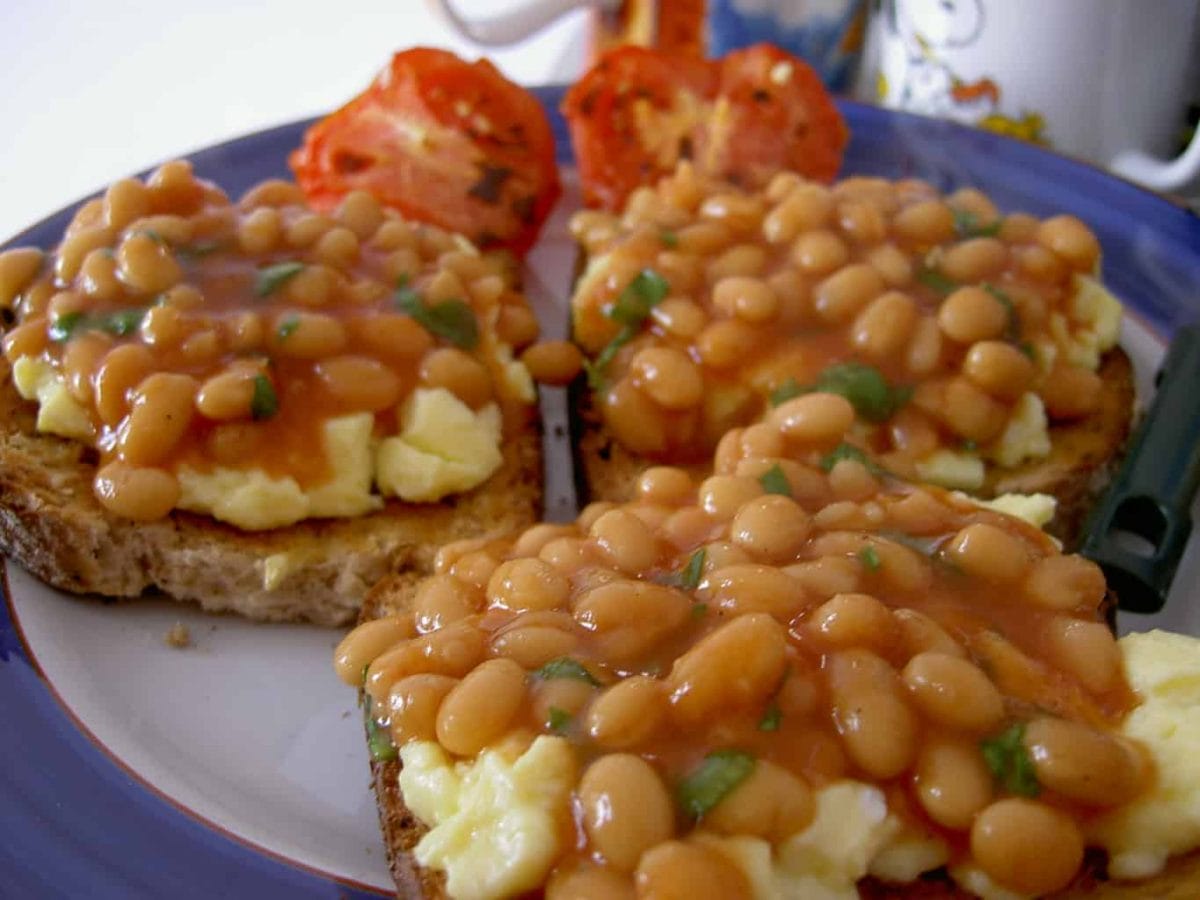 Beans and eggs on toast with tomatoes in the background