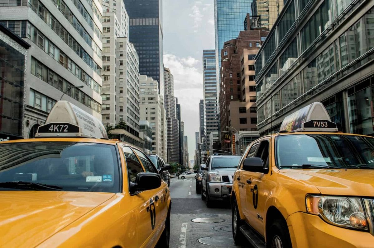 Two New York yellow taxis with skyscrapers behind