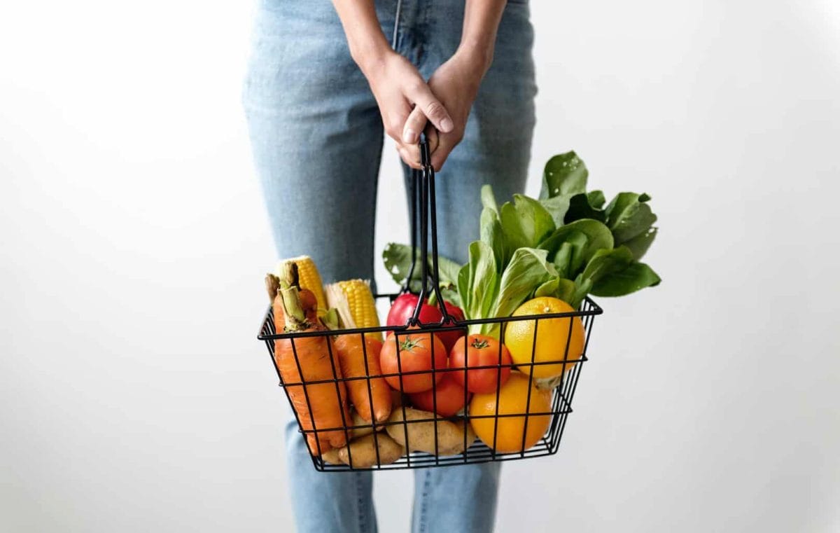 Woman holding shopping basket with food in it