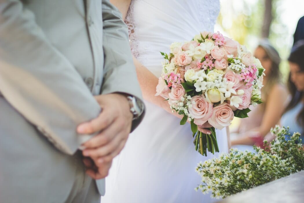 A Groom standing next to a Bride holding a wedding bouquet
