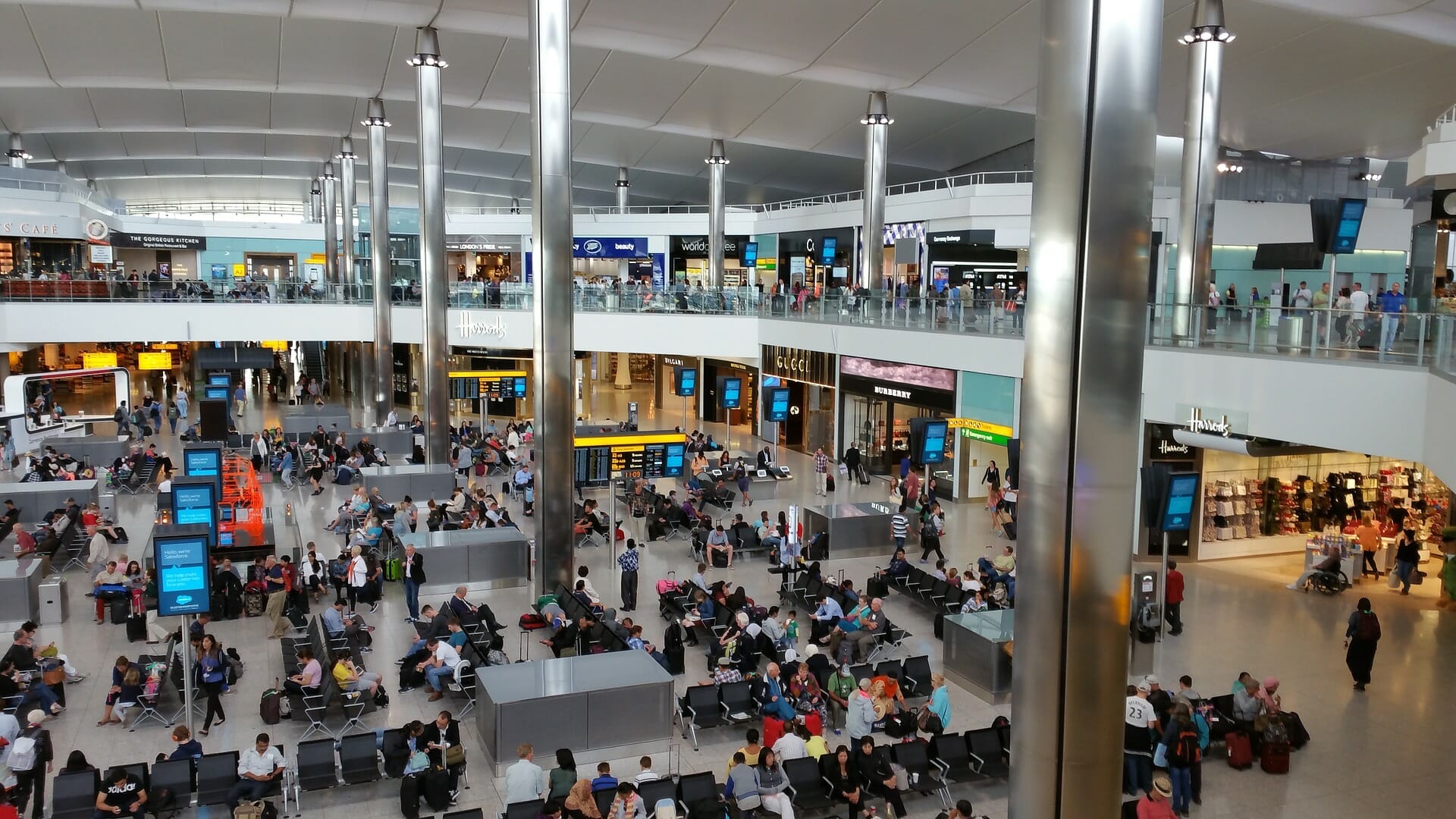 Heathrow airport waiting area with lots of people sitting and standing