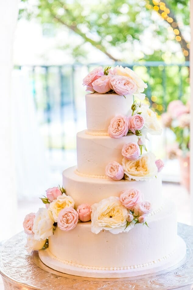 Four tier wedding cake with white and pink roses on it