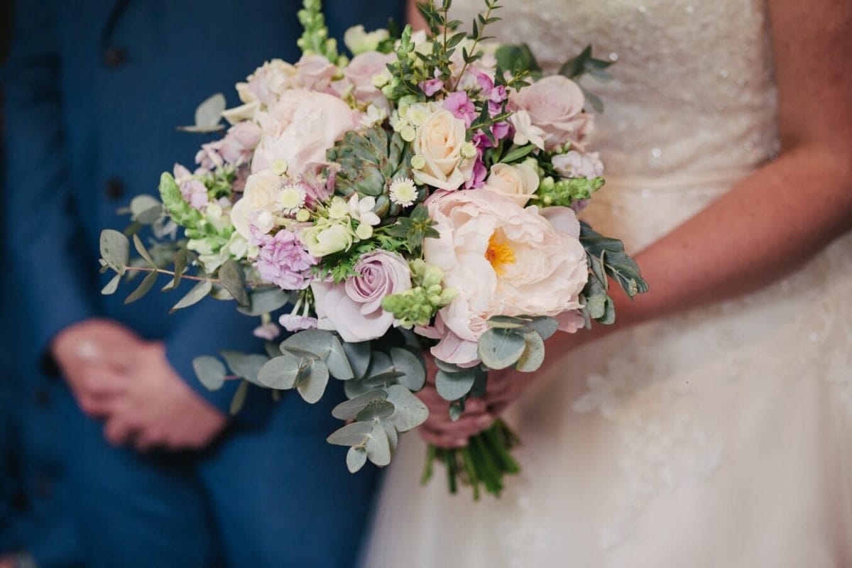 A Bride holding a wedding bouquet next to the Groom