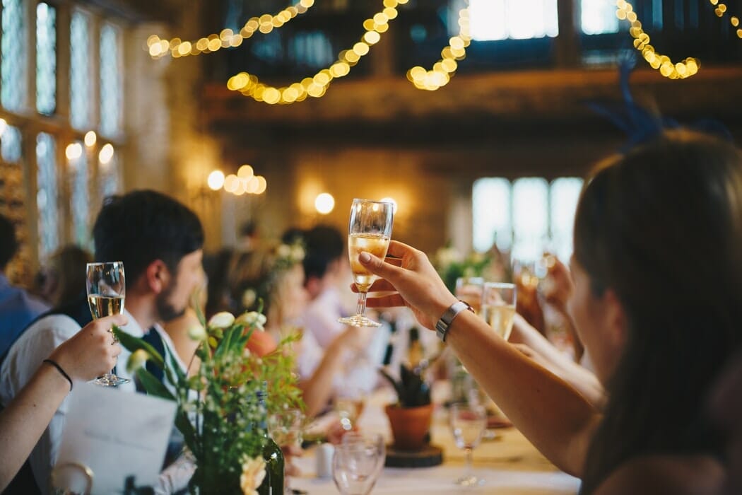 People toasting at a wedding with lights dangling from the ceiling