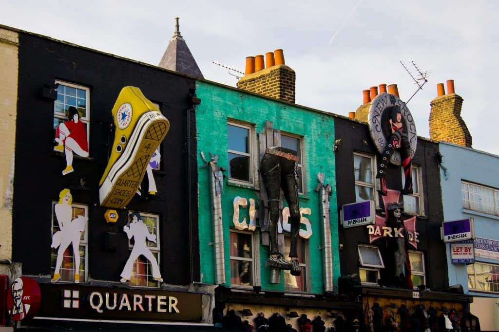 Colorful buildings with large clothing replica statues hanging off exterior walls in Camden London