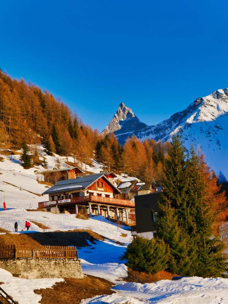 Wooden chalet restaurant built in to mountain surrounded by snow