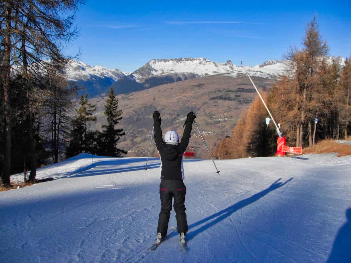 Kalyn skiing with hands raised in victory