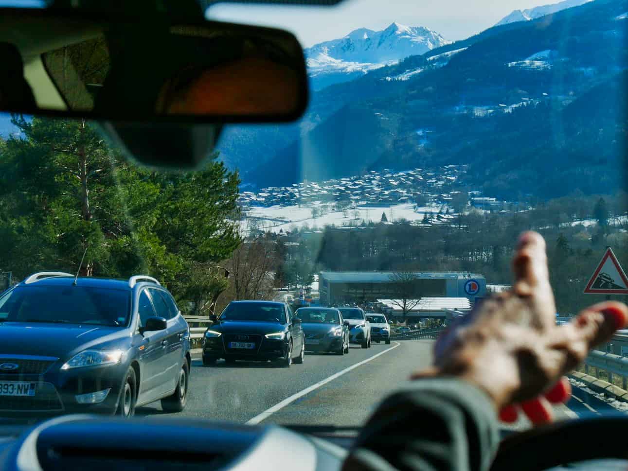 View from inside a car looking out with hand pointing at mountains
