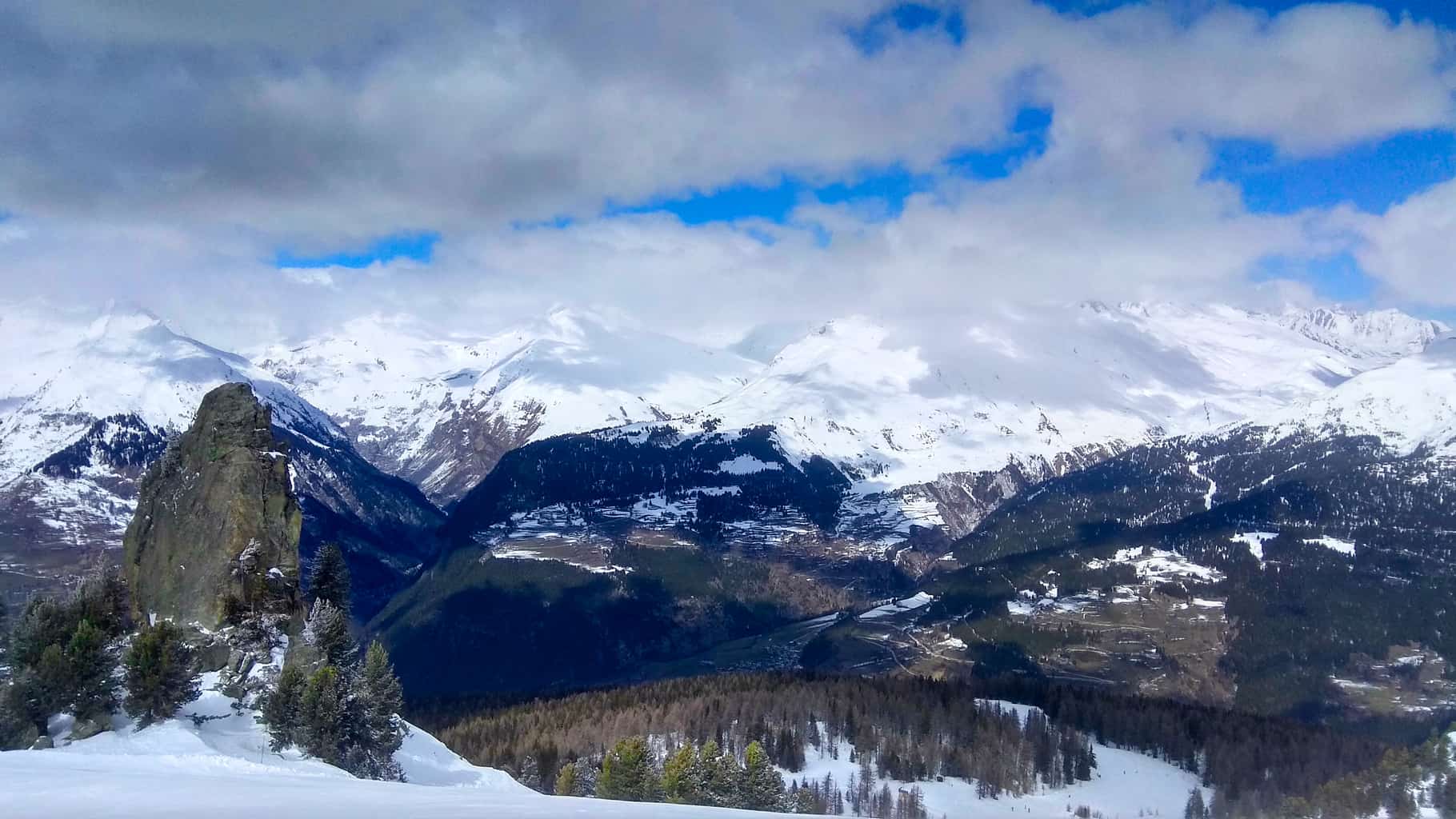 View from Mont Blanc run in Les Arcs looking over valley with clouds and mountains in the background