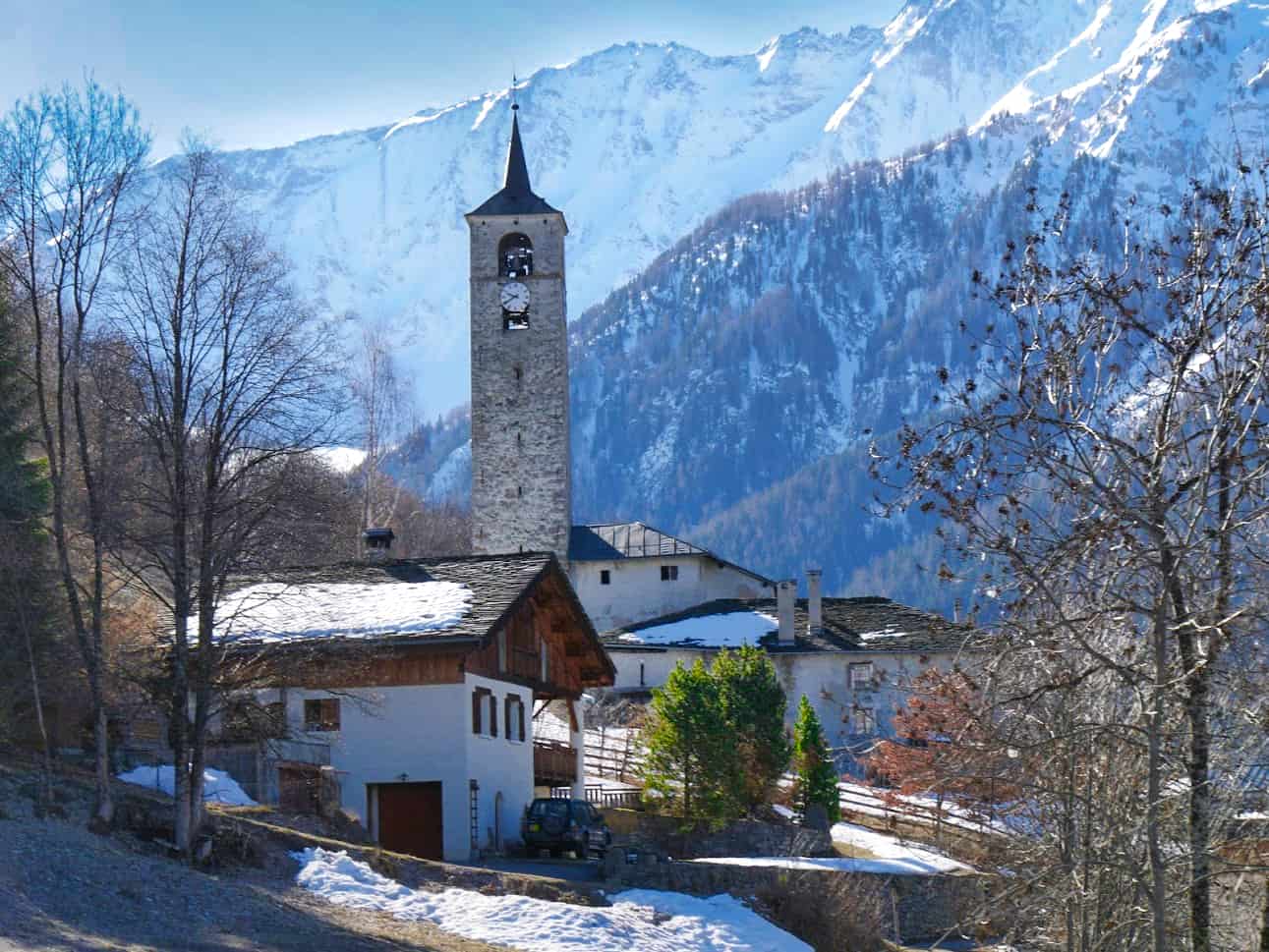 Church seen from ski lift with snowy mountains in the background