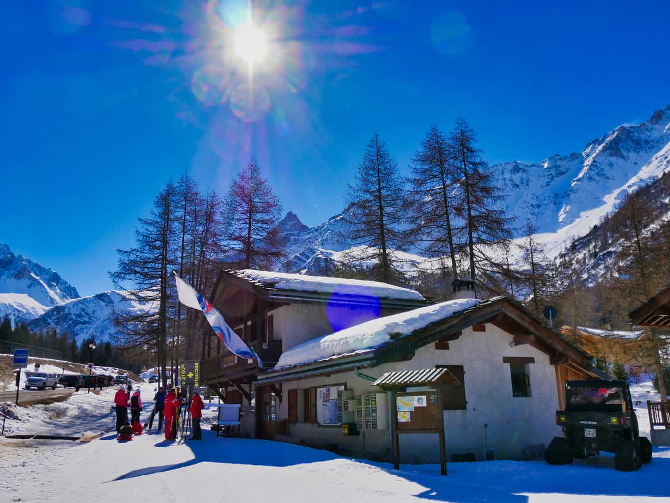 Building surrounded by snow with snowy mountains in the background and deep blue sky