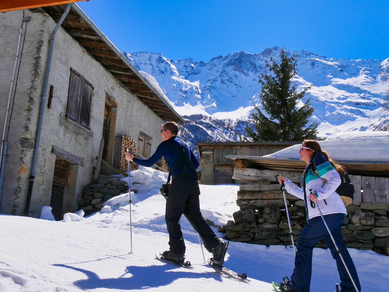 Kalyn and Guy snow shoe walking past buildings in Nordic Ski Area