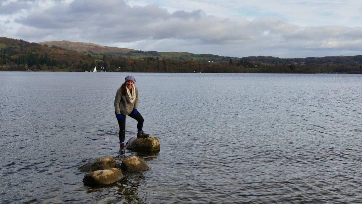 Kalyn standing on rocks in the middle of a lake surrounded by water