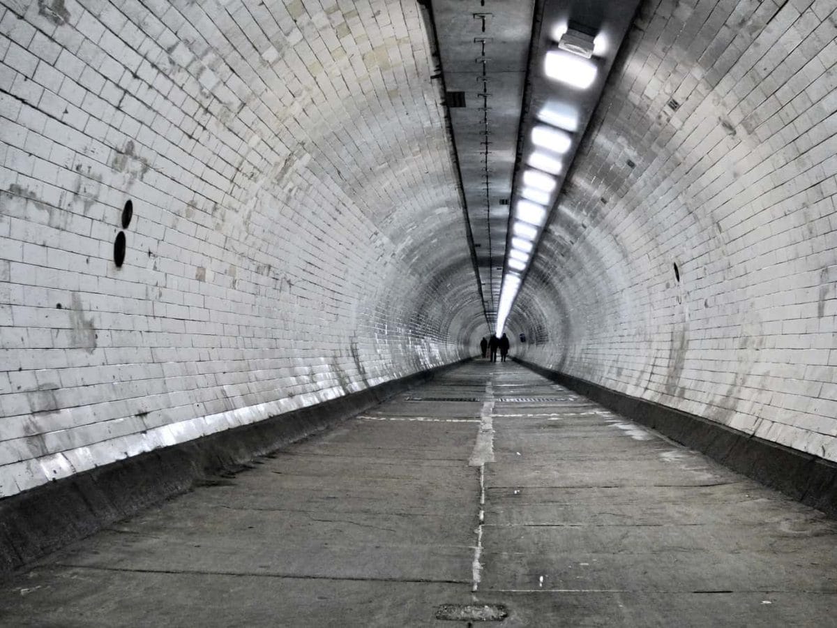 An almost empty London Underground passage with people right at the end