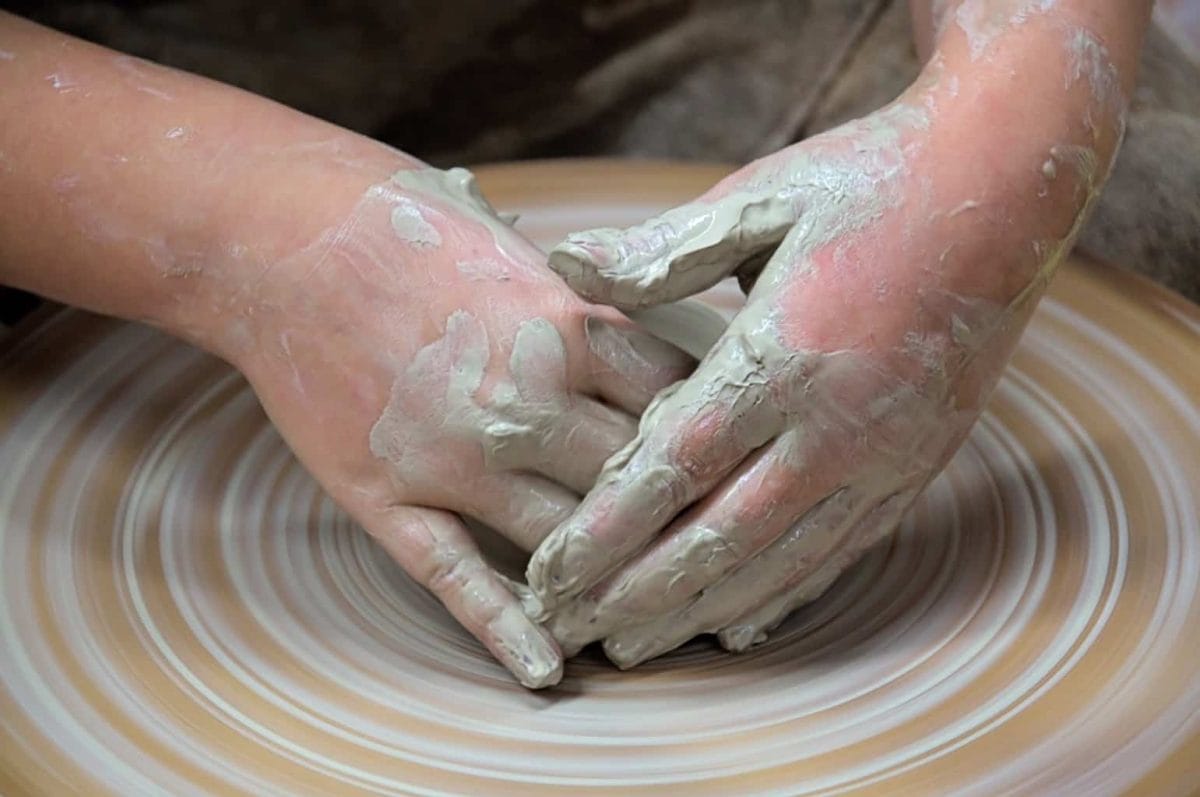 Hands moulding clay on a spnning wheel