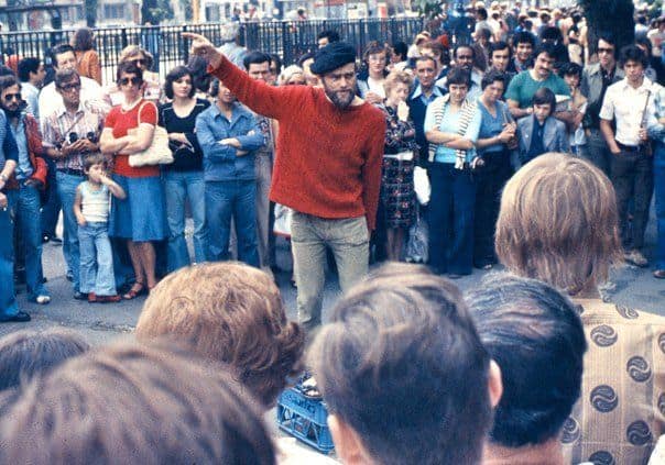 A man in a red sweatshirt and blue beret at Speakers Corner in London surrounded by people in 1974