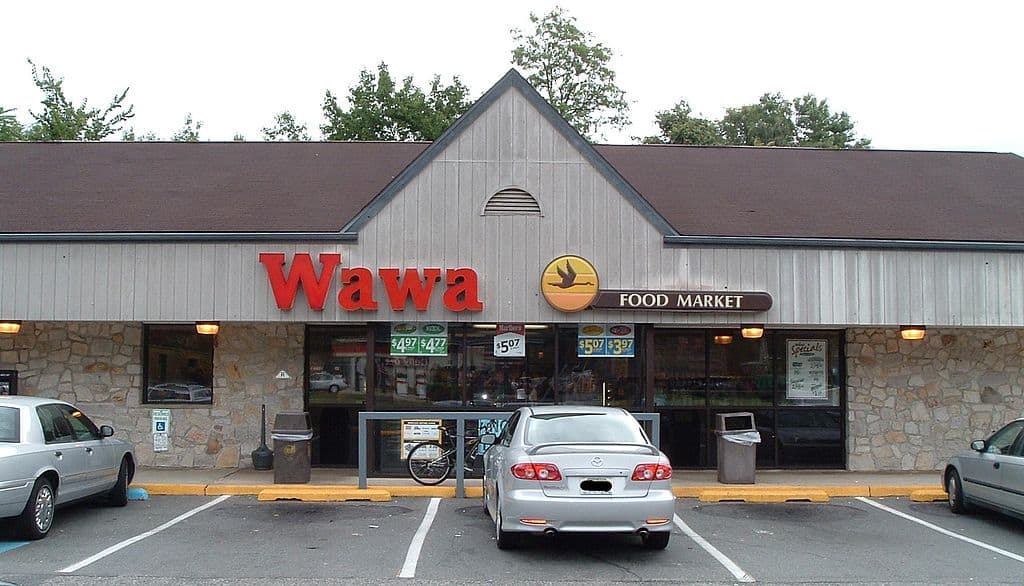 A Wawa food market store with cars in front