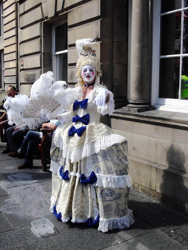 An actor on the streets of Edinburgh dressed in a dress with a wig