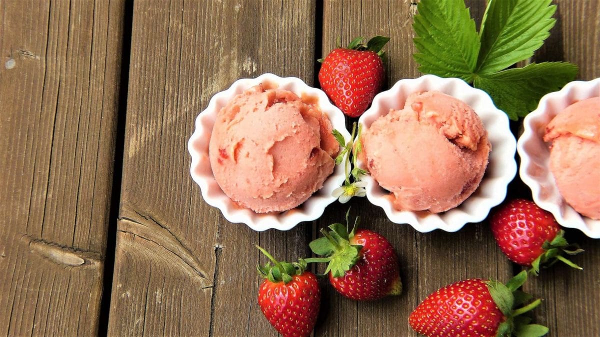 Three balls of strawberry ice cream in white dishes