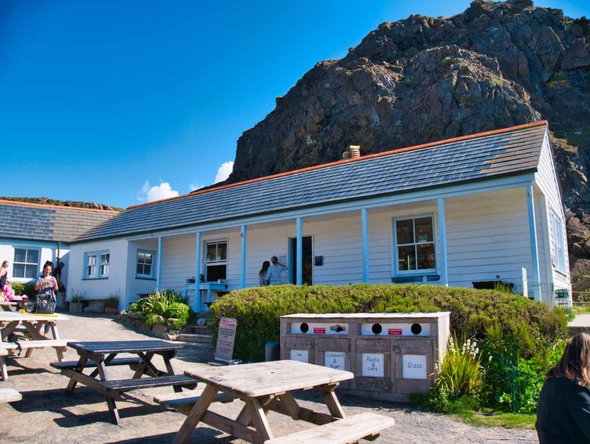The cafe at Kynance Cove with picnic tables outside and a blue sky