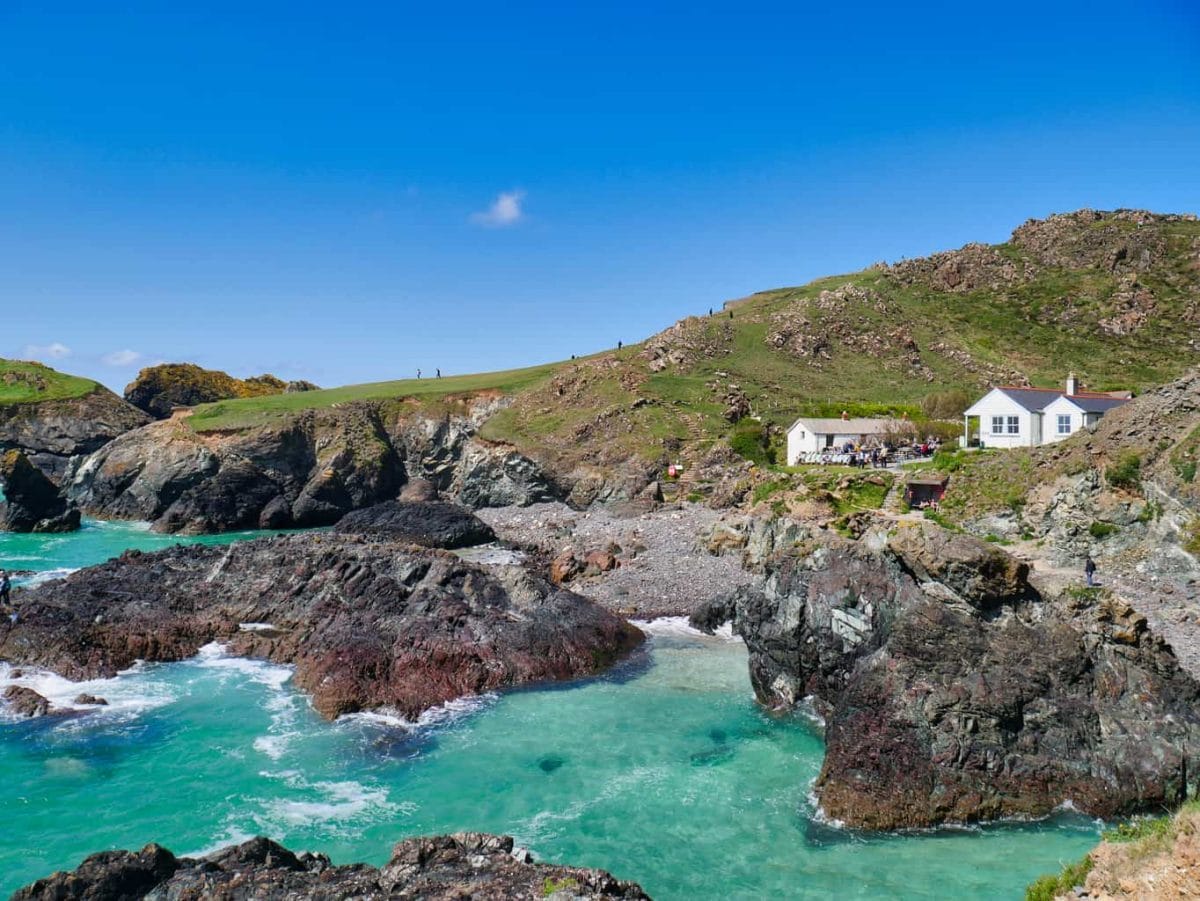 Kynance Cove with incredible blue water and a view of the white cafe building