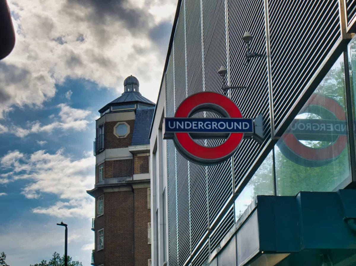 A London Undergound sign with ominous clouds and a building behind