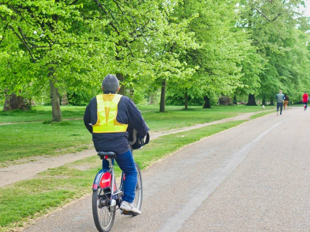 A man in a flourescent jacket cycling in Hyde Park