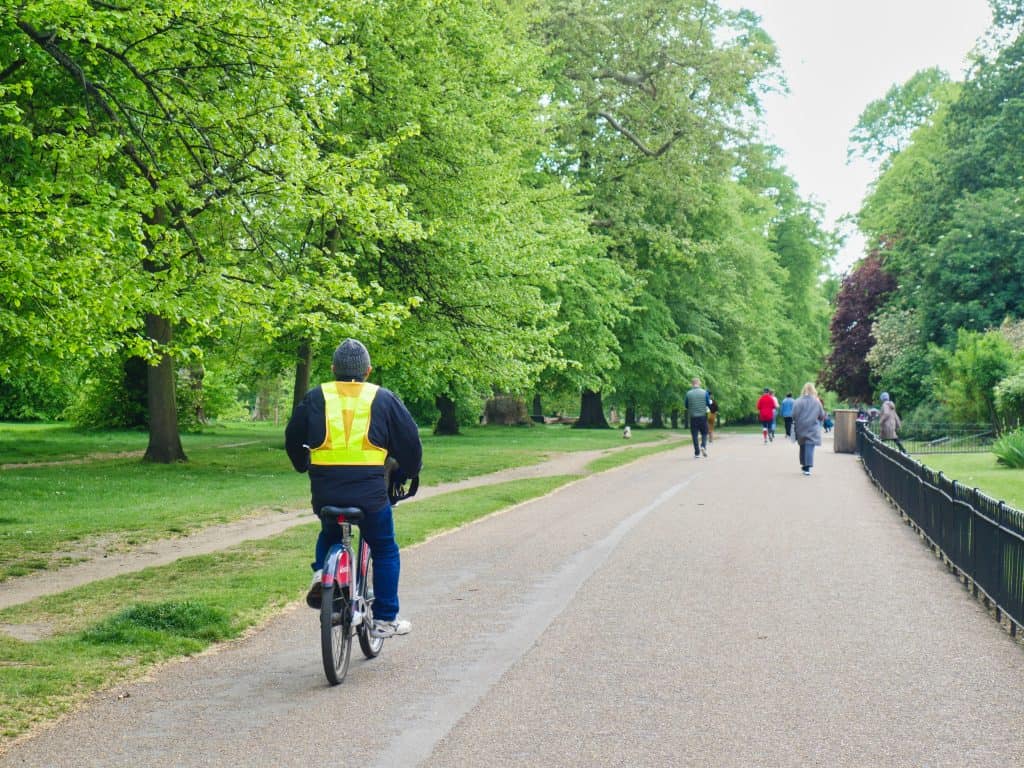 A man in a flourescent jacket cycling in Hyde Park