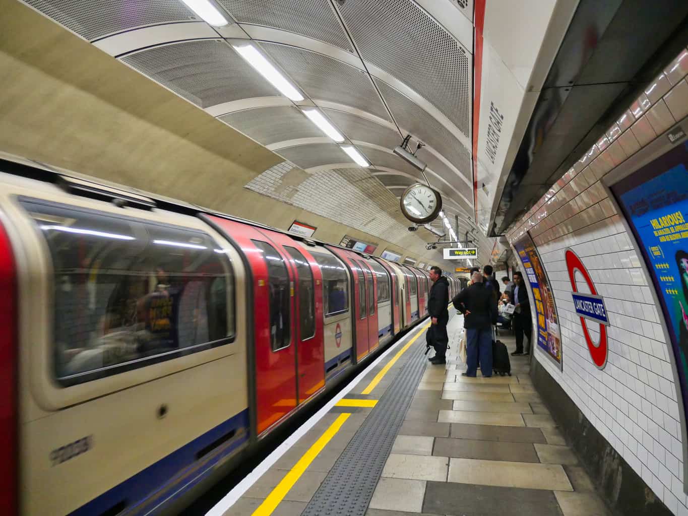 A London Underground train waiting at Lancaster Gate with people waiting to get on