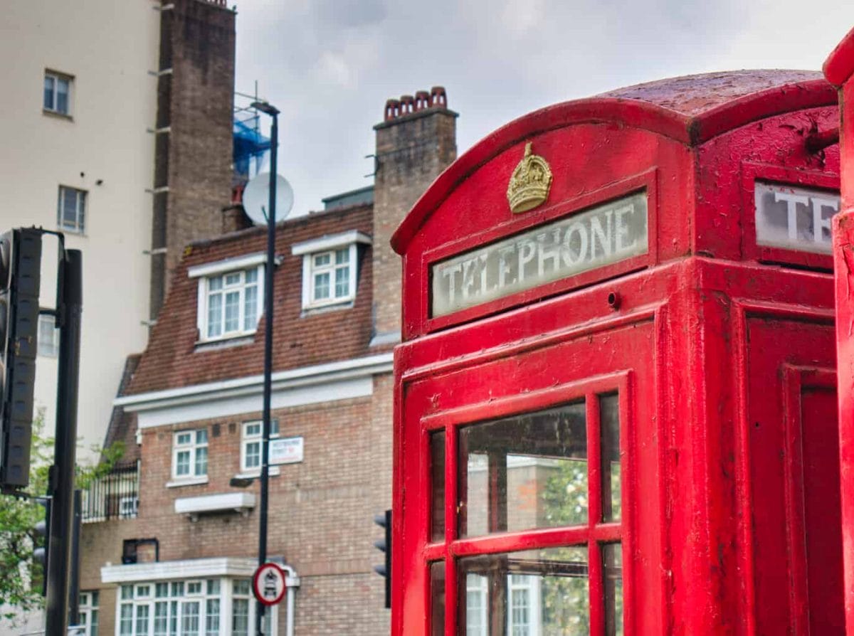 A red telephone booth in London with a building behind