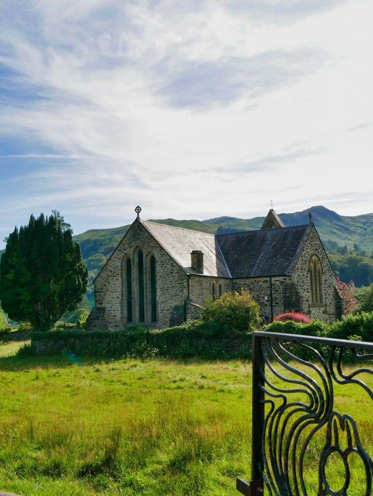 A church in Beddgelert Wales with hills behind
