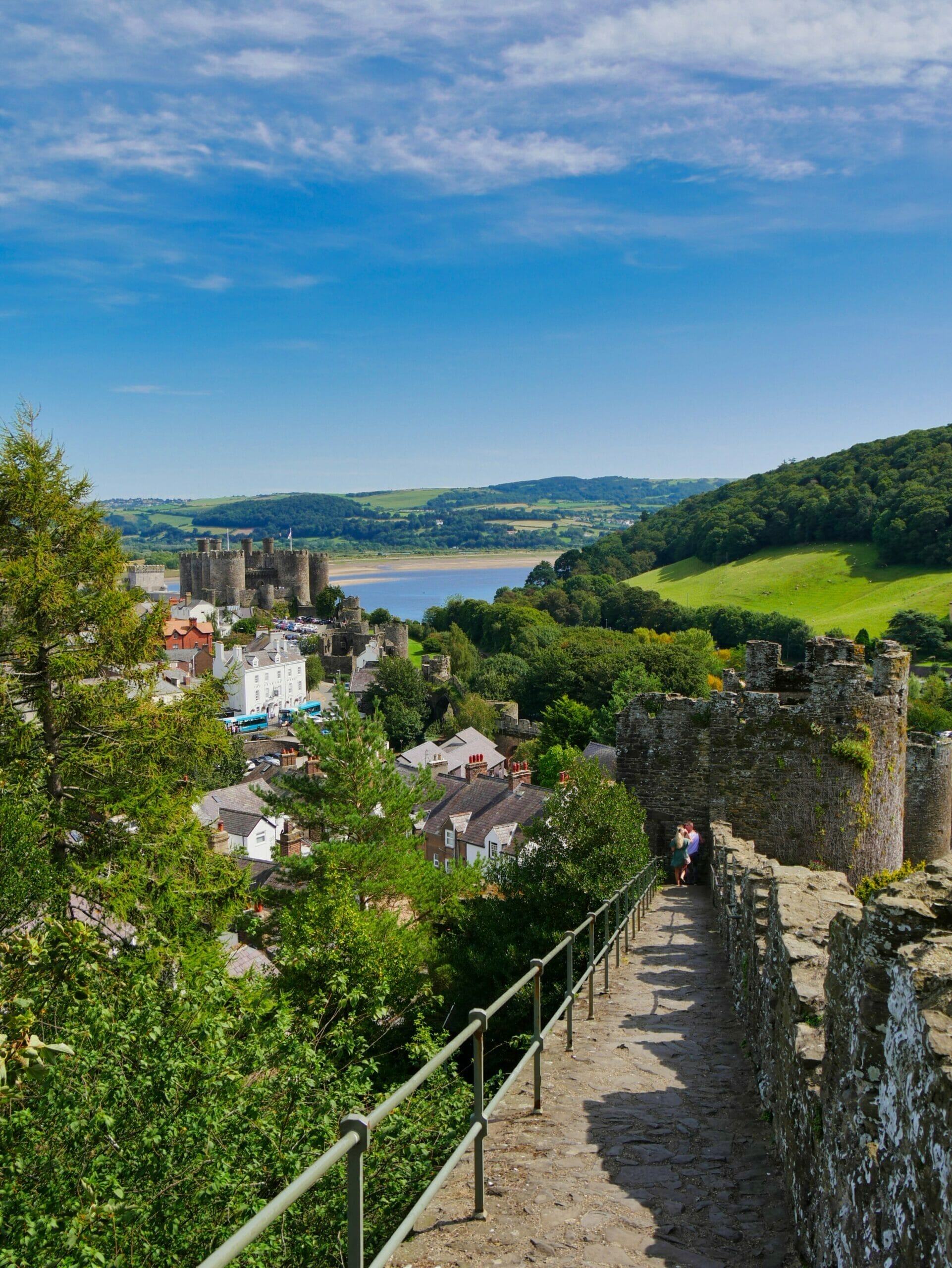 Walls around Conwy in Wales with castle, water, and hills in the background