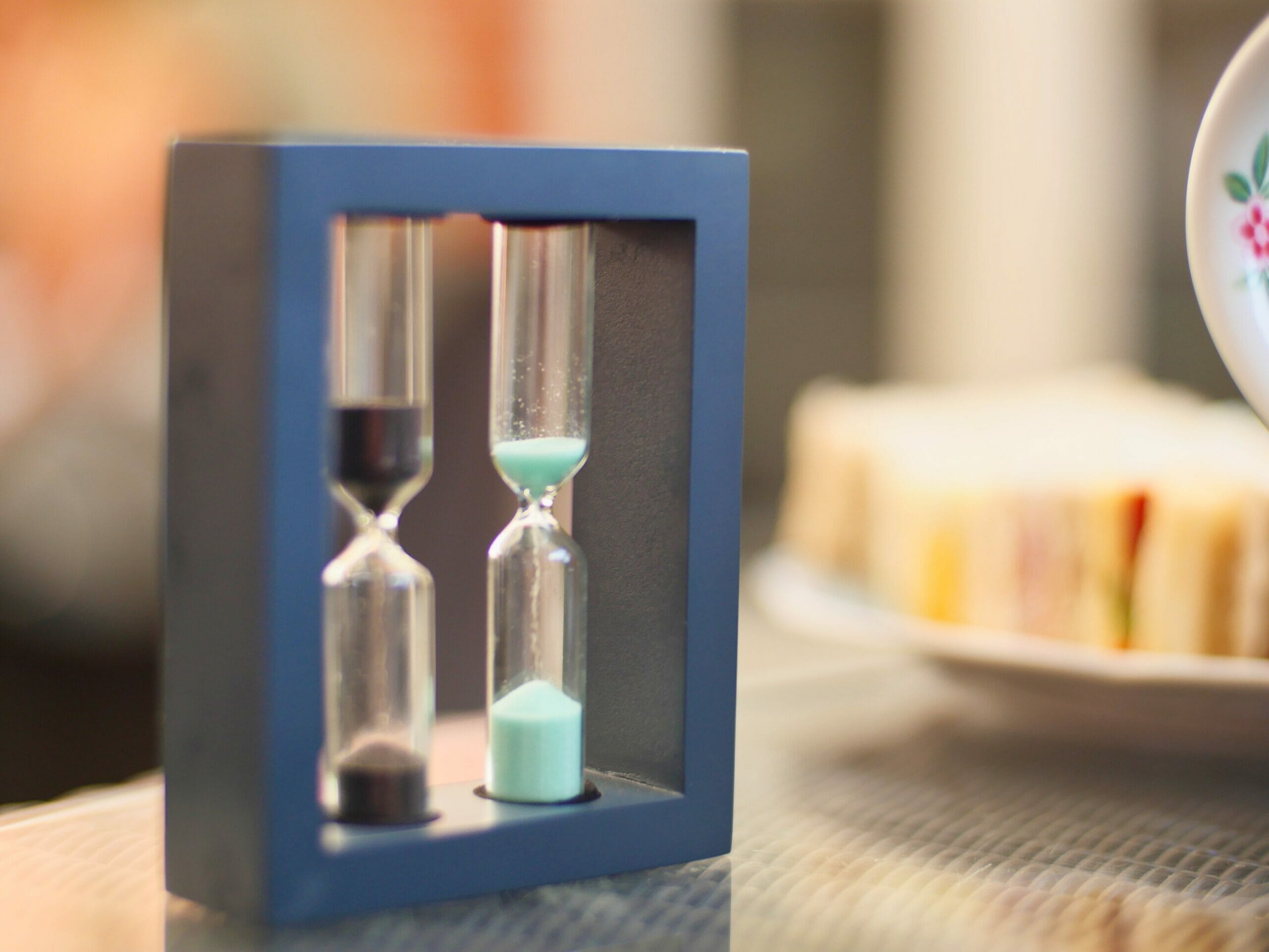 A tea timer with two sand timers, one with black sand and one with light blue sand