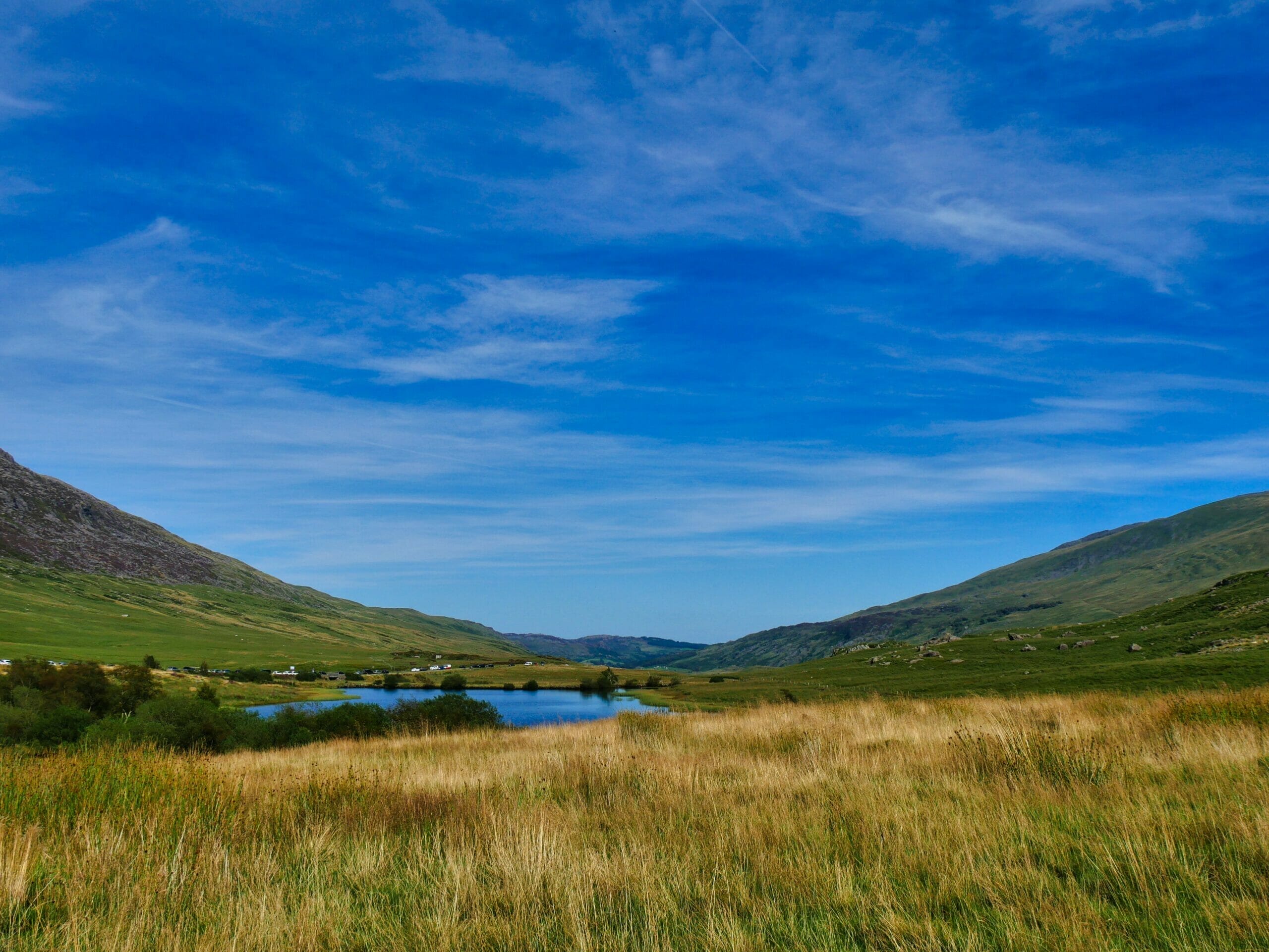 Lush green hills on either side of a valley with deep blue sky in Wales