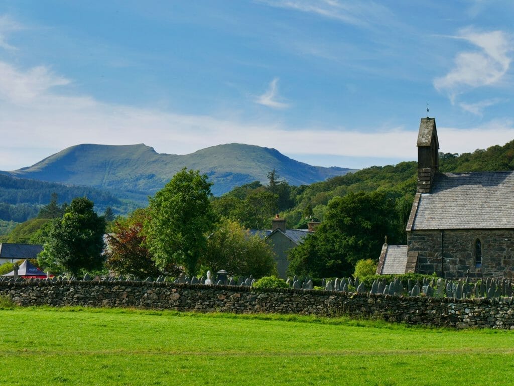 A field and church in Beddgelert, Wales, with a hill in the background