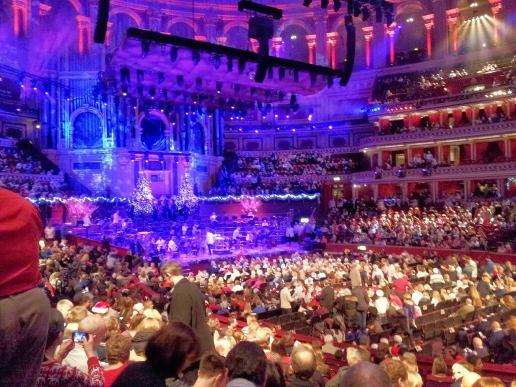 A full audience at The Royal Albert Hall for Christmas carols, with people wearing red hats