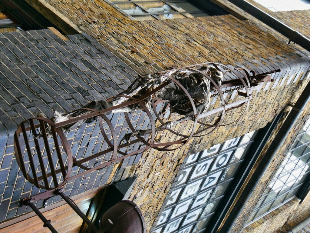 A skeleton in a cage hanging outside the Clink Prison Museum