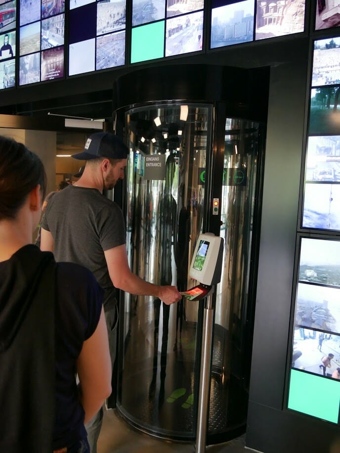 A man scannig his ticket to enter the German Spy Museum, designed to make it feel like you are going through an airport security gate