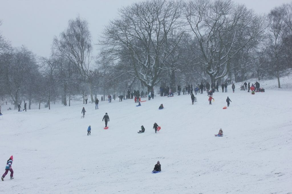 Lots of people sledding in the snow in Greenwich Park, London
