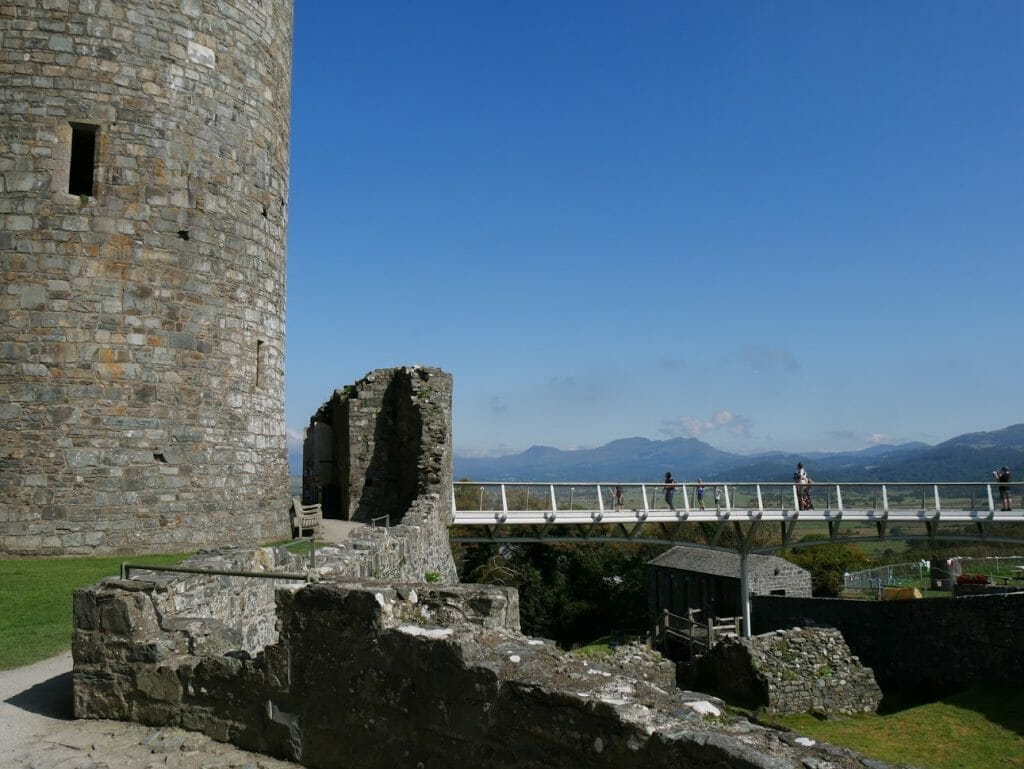 A bridge leading to Harlech Castle with mountains in the background