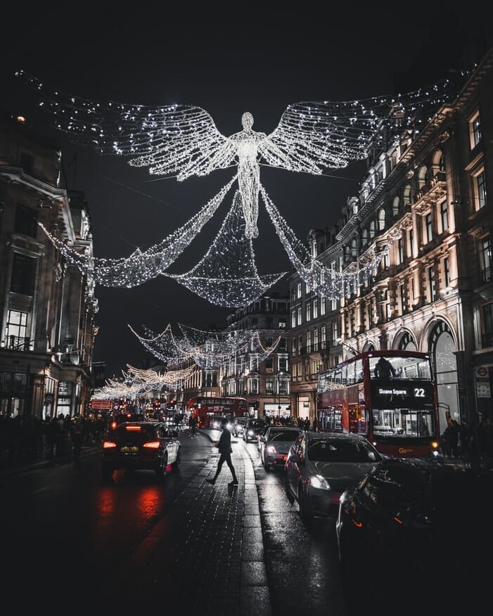 Christmas lights in London with traffic jam and London buses. One of the sets of lights is designed to look like an angel.