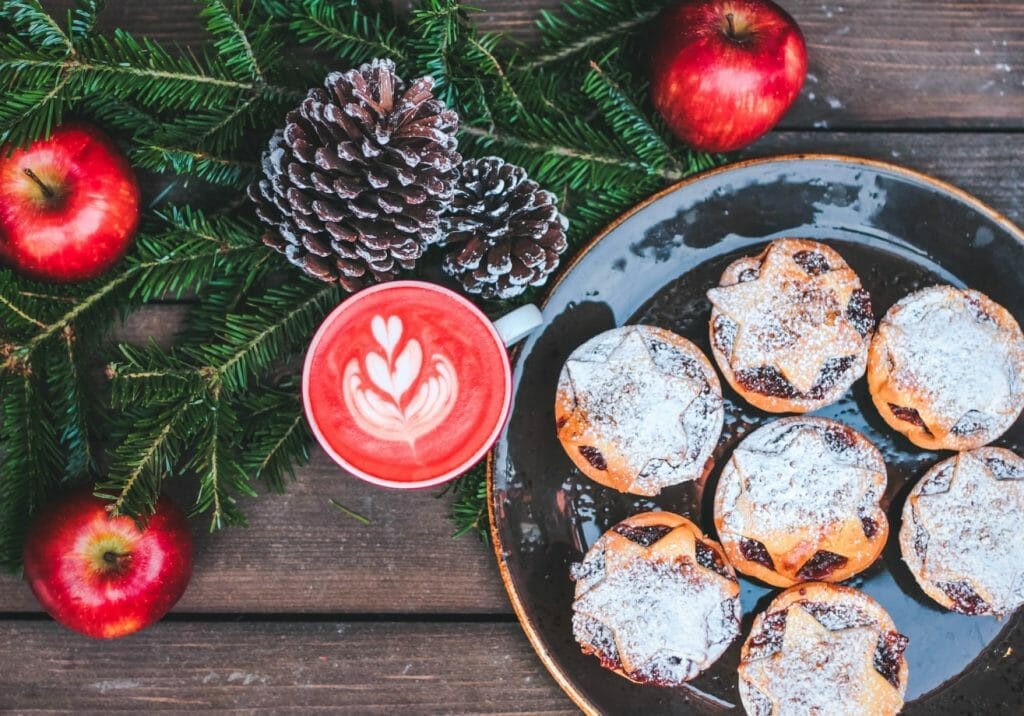 Mince pies with red drink and cones with apples