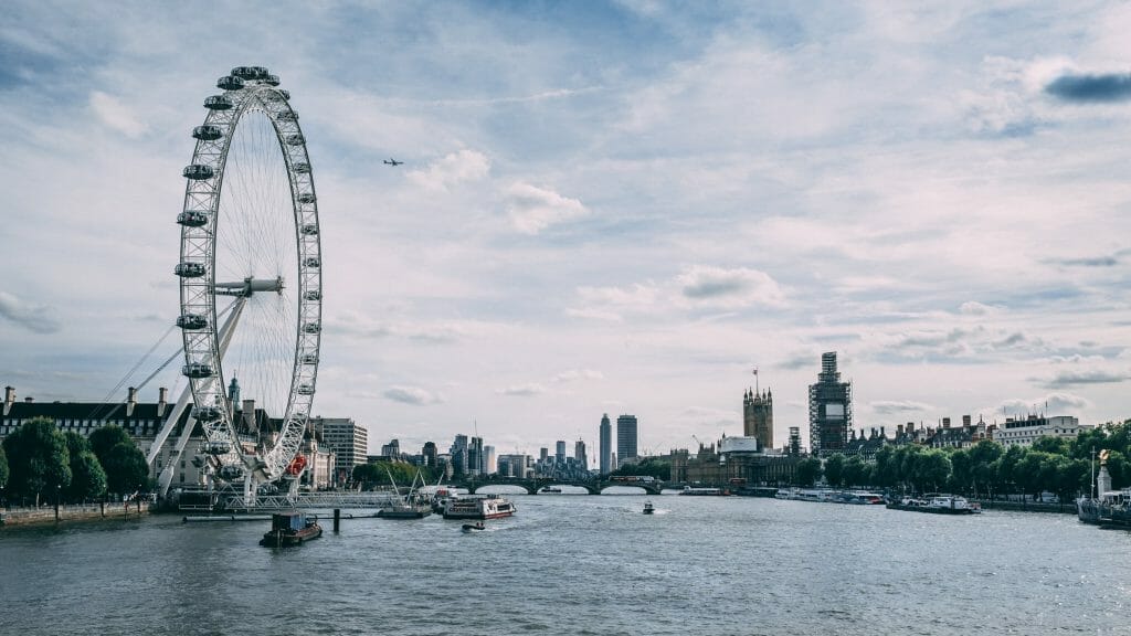 River Thames with London Eye and Plane in sky and boats on the river