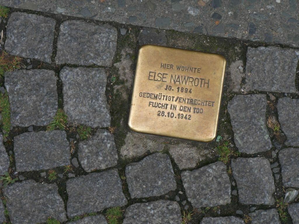 A golden memorial plaque in a cobbled sidewalk in Berlin