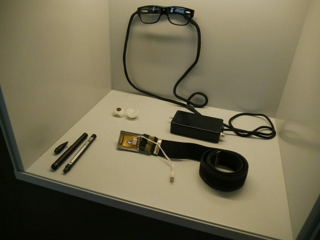 Some spy devices at the German Spy Museum, Berlin. A false eye, glasses with in-built camera, belt device, and pen device.
