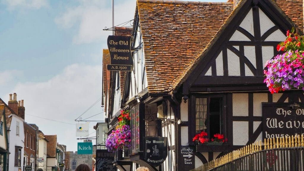 An old AD 1500 building with black wooden beams and restaurant signs on it in Canterbury